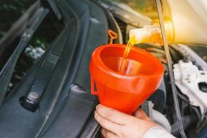 Car mechanic replacing and pouring oil into engine photo