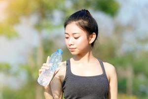 mujer deportiva bebiendo agua en un día soleado foto