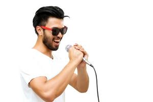 Hombre asiático con bigote cantando en micrófono sobre fondo blanco. foto