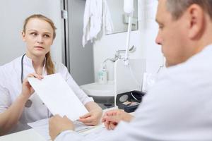 enfermera le muestra a un médico una hoja de papel en blanco foto