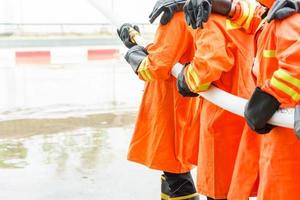 Firefighters using extinguisher and water from hose photo