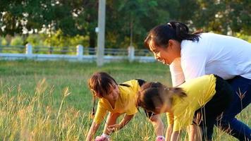glad mamma och döttrar som leker och springer i fältet