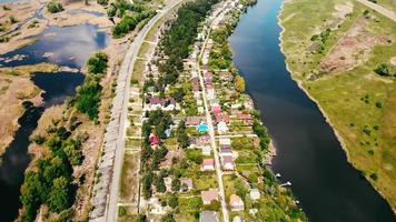 Vuelo sobre el campo y el río, cerca de un pequeño pueblo, verano. video