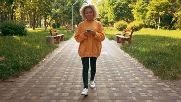 mujer joven, ambulante, en el parque, utilizar, móvil