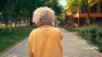 Back view blonde woman walks in park video