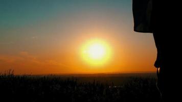 Vue arrière d'un couple marchant vers le coucher du soleil video