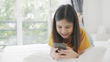 donna sdraiata sul letto e utilizza lo smartphone video