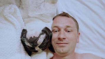 close up van een man met zijn hond in bed video