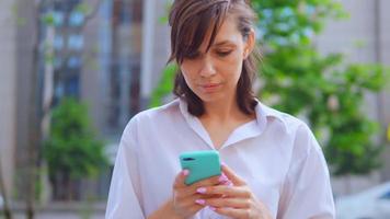 mulher sorridente segurando um smartphone com um meio urbano video