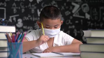 un niño con una máscara está aprendiendo a escribir video