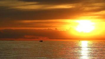 pôr do sol refletido no mar e no barco de pesca video