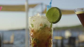 Cocktail on a bar with sun setting into the sea in the background video