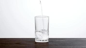 Wasser in ein Glas über den Holztisch gießen