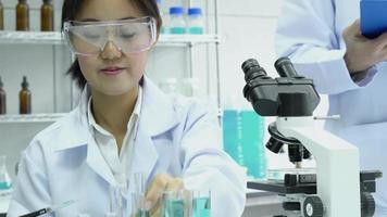 asiatische Frau experimentiert mit Chemikalien im Labor. video