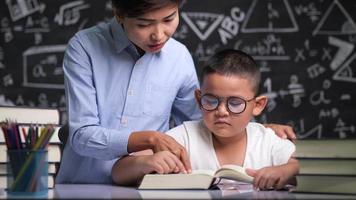 Tutor teaching a child to read a book video