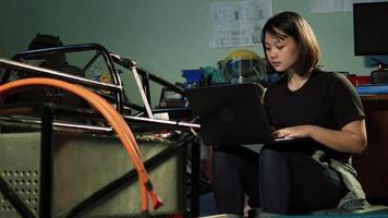 mujer ingeniera que actualiza el software en una computadora portátil en el garaje. video