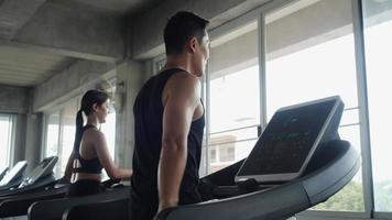 Athletic man and woman exercising on treadmills at fitness gym video