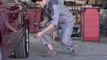 uomo tecnico che controlla la pressione dei pneumatici in un garage. video