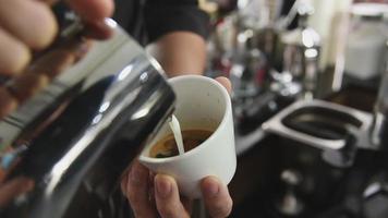 Barista pouring milk on latte coffee