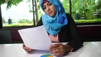 Young Arabic woman thoughtfully looking at paper chart