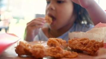 Kind, das gebratenes Huhn und Pommes Frites in einem Geschäft isst video