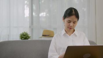 Asian woman using laptop on sofa video