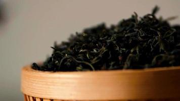 folhas secas de chá chinês caindo em uma tigela de madeira