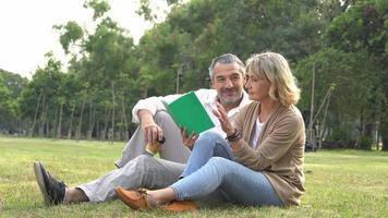 um casal lendo um livro sentado no parque video