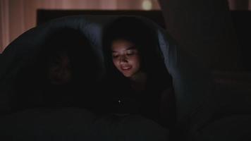 par tonåriga tjejer under en filt tittar på mobiltelefoner video