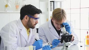 equipo de científicos usando un microscopio y escribiendo un informe video