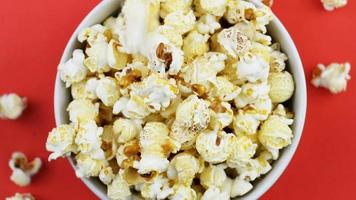 Pop-corn tombant dans un bol blanc sur fond rouge video