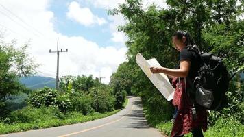 vrouw backpacken met kaart langs de weg. video