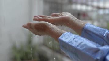 bras en imperméable bleu attrapant la pluie devant la maison. video