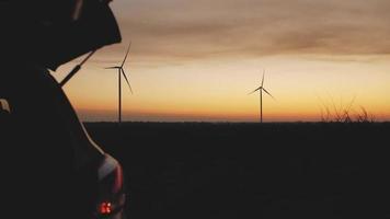 estações de energia eólica e um carro ao pôr do sol