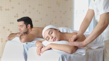 vrouw krijgt massage naast man in spa kamer met daglicht