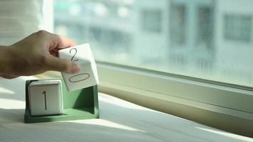 Hand Changing a White Wooden Calendar Block from 12 to 13 video