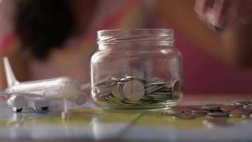 menina colocando dinheiro em uma jarra de vidro por um brinquedo de aeronave.