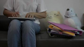 vrouw zittend op een leren bank en tablet met documenten rond.
