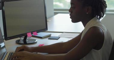 Afroamericana en la oficina escribiendo en la computadora video