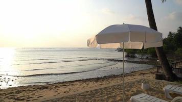 weißer Regenschirm am Strand während des Sonnenuntergangs video