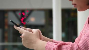 gros plan la main à l'aide de smartphone avec icône coeur rouge
