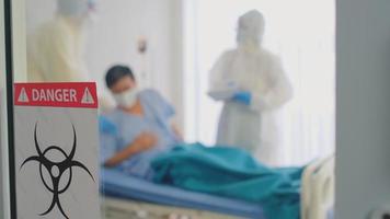 Pancarta de riesgo biológico frente a una habitación de alta protección con un paciente infectado en cuarentena
