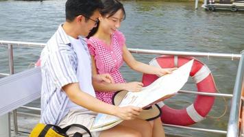 ein Paar, das auf der Terrasse eines Touristenboots sitzt und eine Karte betrachtet