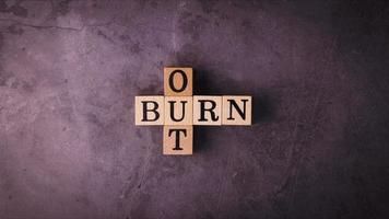 Stoppen Sie die Bewegung des Burnout-Textes mit Holzklötzen auf einem konkreten Hintergrund
