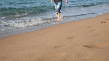 jonge vrouw met spijkerbroek wandelen op het strand video