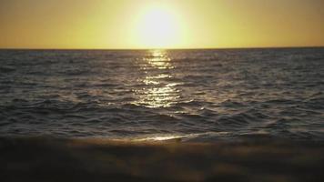 Beach sand and sea surface reflects setting sun video