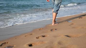 jonge man met spijkerbroek wandelen op het strand