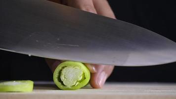 mano sosteniendo un cuchillo y cortando un chile verde fresco video