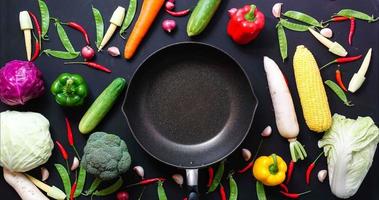 vue de dessus stop motion légumes et une casserole sur fond noir. video