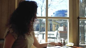 la donna si siede vicino a una finestra e legge un giornale video
